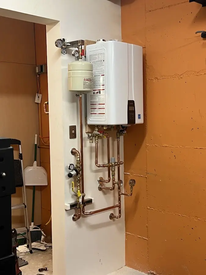 Plumbing technician inspecting water heater connections in St. Simons